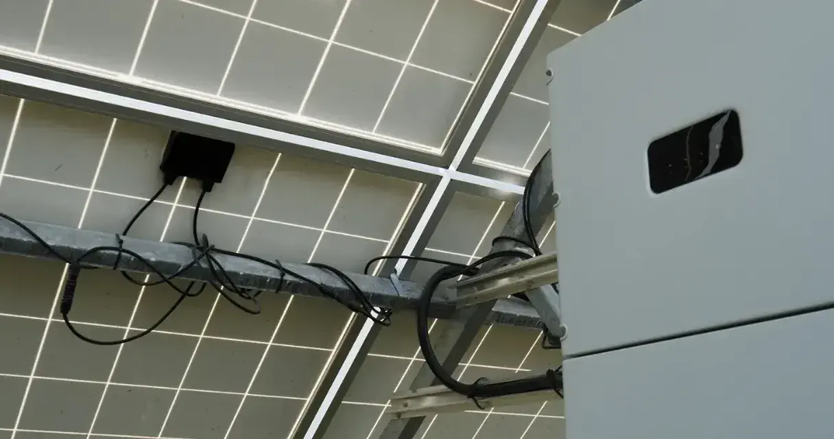 Vista por baixo de uma usina solar: estrutura de fixação, cabeamento e inversor